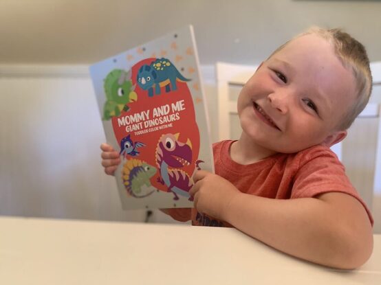 happy boy with a dinosaur coloring book